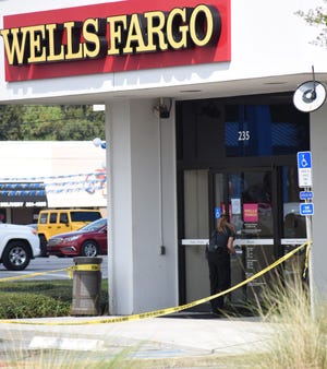 An Escambia County Sheriff's Office crime scene technician dusts the door of the West Nine Mile Road Wells Fargo for fingerprints after a bank robbery Sept. 20, 2018.