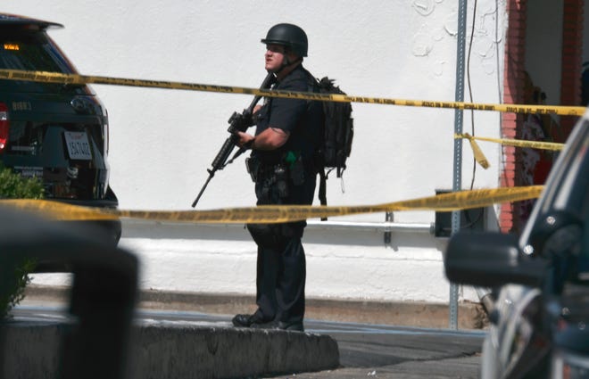 A Los Angeles police offIcer stands guard while police search for a shooting suspect at a Jack in the Box restaurant after a shooting in Van Nuys on Thursday. Police say a male teenage student and a female school employee were wounded.