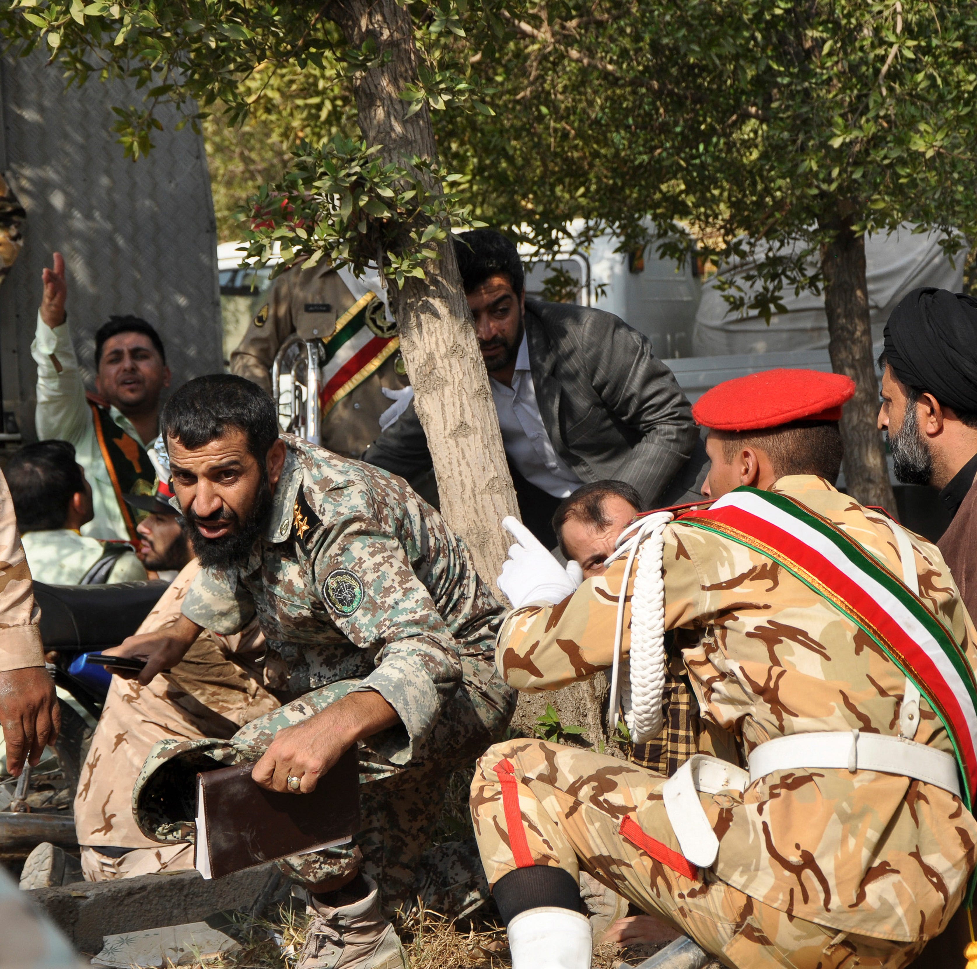In this photo provided by the Iranian Students' News Agency, ISNA, Iranian armed forces members and civilians take shelter in a shooting during a military parade marking the 38th anniversary of Iraq's 1980 invasion of Iran, in the southwestern city o