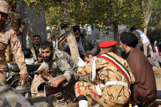 In this photo provided by the Iranian Students' News Agency, ISNA, Iranian armed forces members and civilians take shelter in a shooting during a military parade marking the 38th anniversary of Iraq's 1980 invasion of Iran, in the southwestern city of Ahvaz, Iran, Saturday, Sept. 22, 2018.