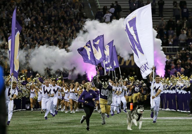 Dubs II, the Washington Huskies live mascot, leads the team out of the tunnel before Saturday's game against Arizona State in Seattle. Husky coaches (and fans) have complained about evening kickoffs, but given the television ratings such games draw, the Pac-12 After Dark is likely here to stay.