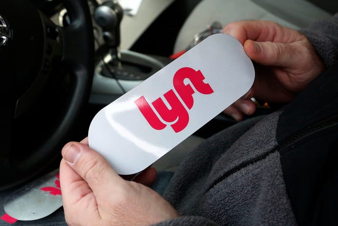 A Lyft driver holds a Lyft logo before installing it on his car in Pittsburgh in January 2018.