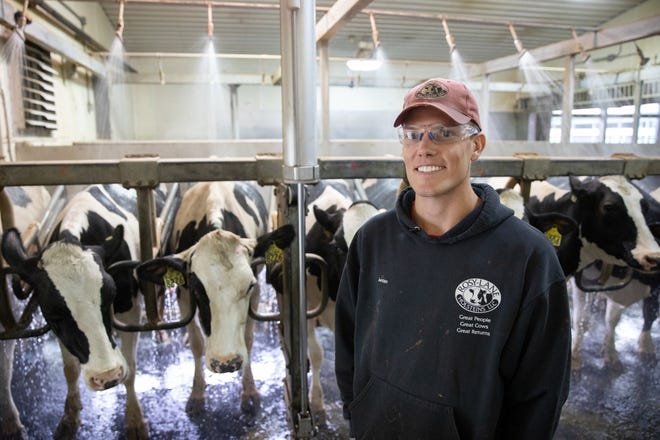 Jordan Matthews, one of four partners at Rosy-Lane Holsteins, poses for a picture near milking parlor showers that have been installed and are in use at Rosy-Lane Holsteins in Watertown, Wis., Wednesday, Aug. 29, 2018. The showers, which help cool the cows on warm days, are aimed at their backs and away from their udders and faces.