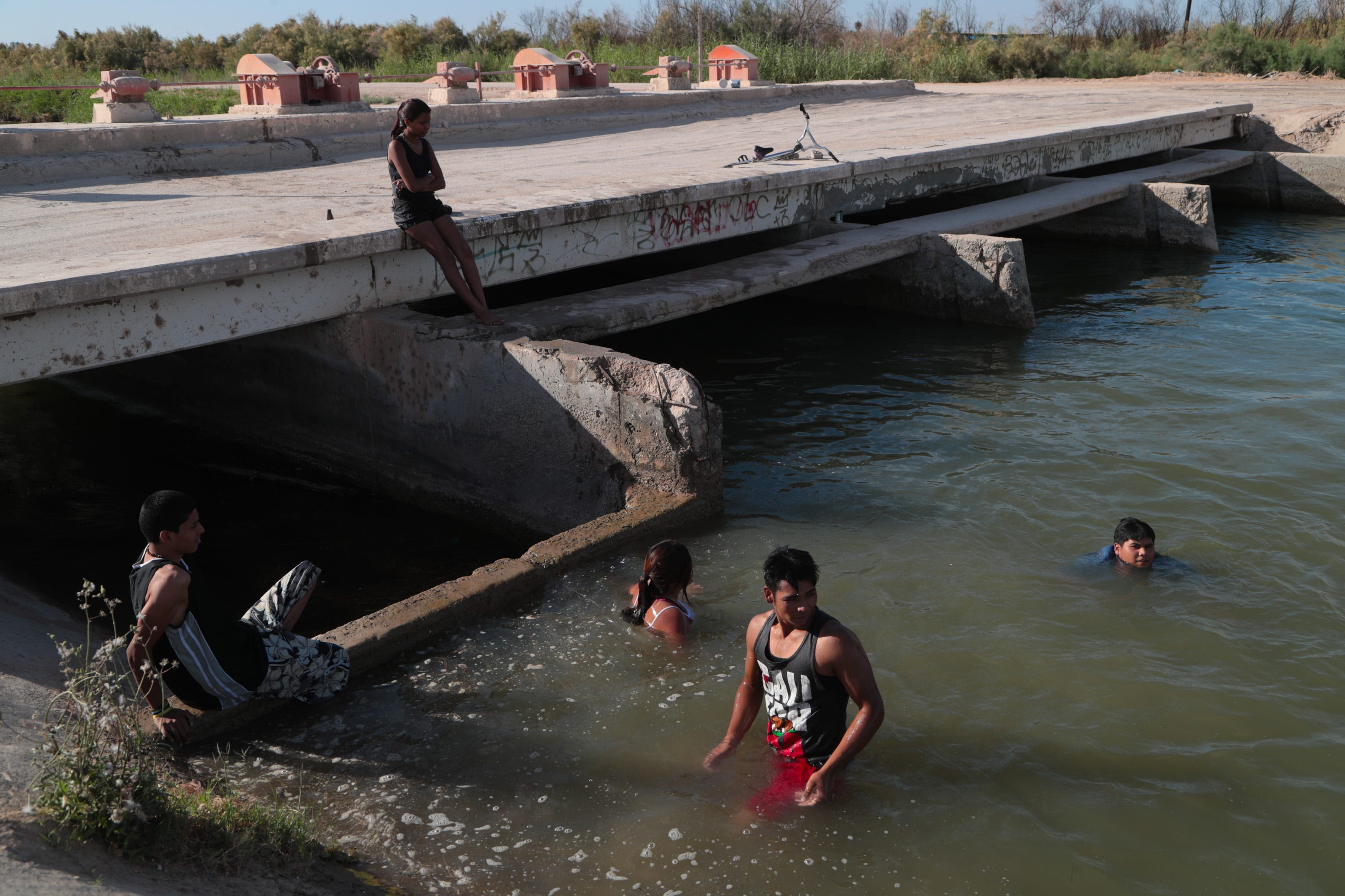 Teenagers swim in the Pacífico Canal in the Mexicali Valley. Their parents work as "pepenadores," or waste pickers, in a nearby dump.