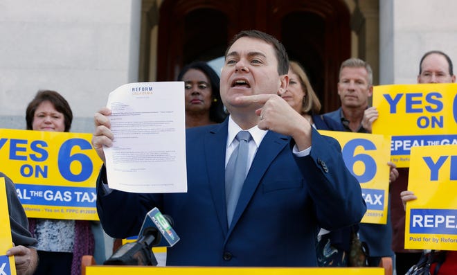 Carl DeMaio, who lead the Proposition 6 campaign to repeal a gas tax increase, shows off ballot measure he proposed to provide money for road repairs and eliminate the state high-speed rail plan in this Associated Press file photo.