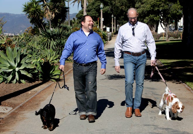 In this Feb. 23, 2012, photo, Steven May, right, walks with his dog, Winnie beside his attorney, David Pisarra, with his dog, Dudley in Santa Monica. A new law signed by Gov. Jerry Brown gives judges the discretion of applying rules similar to those in child-custody cases when determining who gets the family pet following a divorce. It takes effect Jan. 1, 2019.