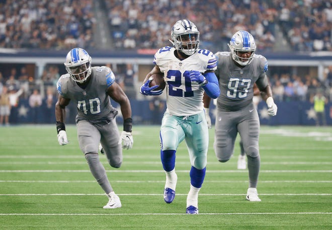 Dallas Cowboys running back Ezekiel Elliott carries the ball as Detroit Lions linebacker Jarrad Davis (40) and defensive end Da'Shawn Hand (93) give chase in the first half.