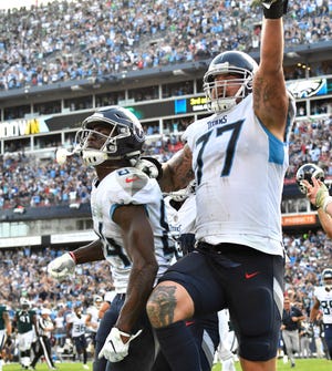 Titans offensive tackle Taylor Lewan (77) and wide receiver Corey Davis (84) celebrate the game-winning touchdown catch in overtime Sunday.