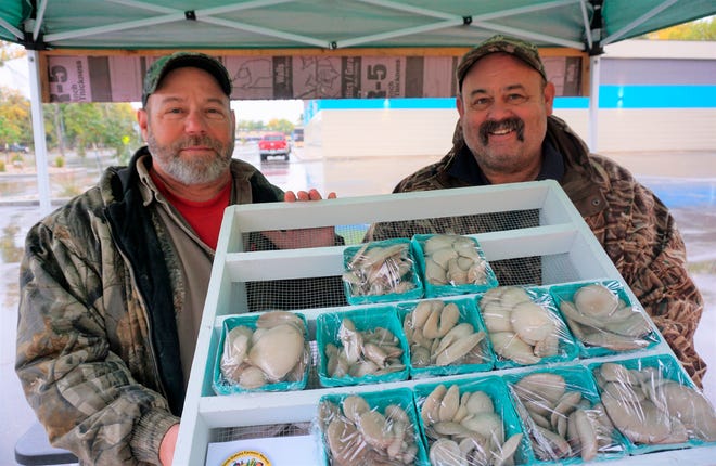 In this Sept. 20, 2018, photo, Dan, left, and Jeff Coggins hold a tray of some of the oyster mushrooms available at their farmers market booth in Minot. The brothers have found success in their second year harvesting mushrooms and selling their product at local farmers markets.