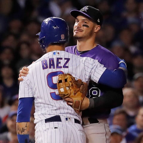 Javier Baez hugs Rockies third baseman Nolan...