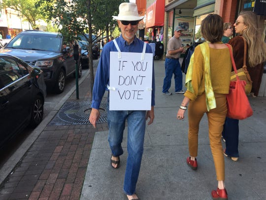 Tom Boynton, 76, of Traverse City walks through downtown Traverse City wearing a lunchboard sign that reads on the front 