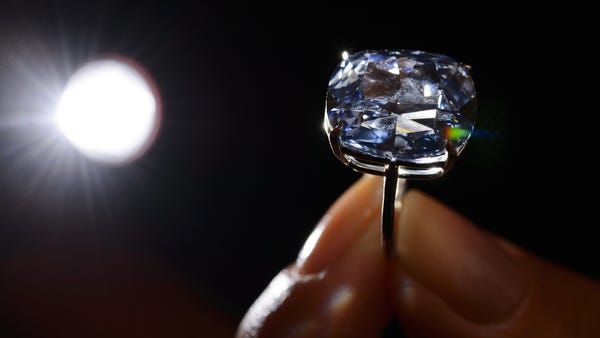 A model holds a 12.03-carat blue diamond during a...