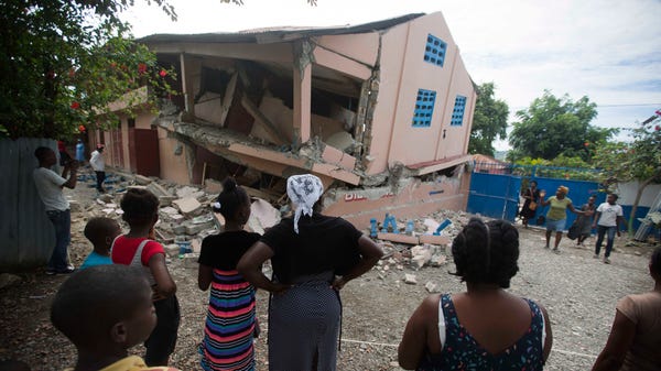 Residents stand looking at a collapsed school...