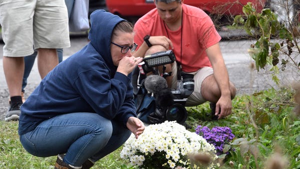 A woman kneels after placing flowers, Sunday,...