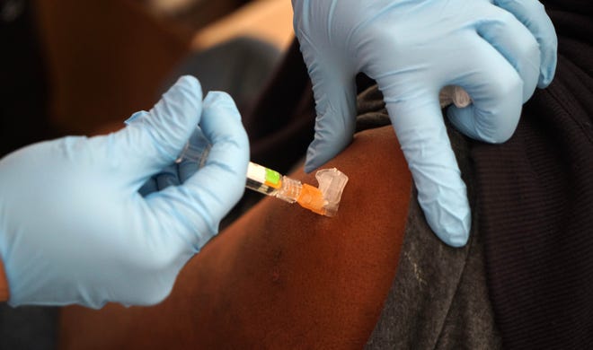 A flu shot is administered in the arm of a person visiting the annual free flu shot event held by the Division of Public Health at the Porter State Service Center.