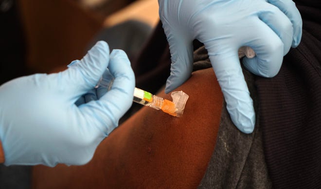 A flu shot is administered in the arm of a person visiting the annual free flu shot event held by the Division of Public Health at the Porter State Service Center.