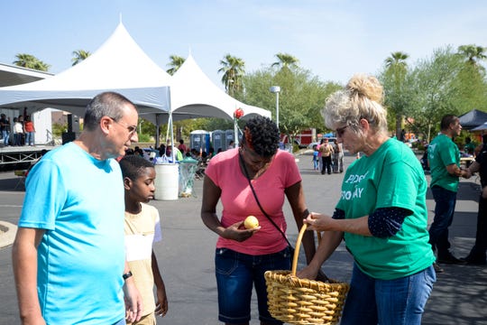 A volunteer passes out free apples at Phoenix Food Day.