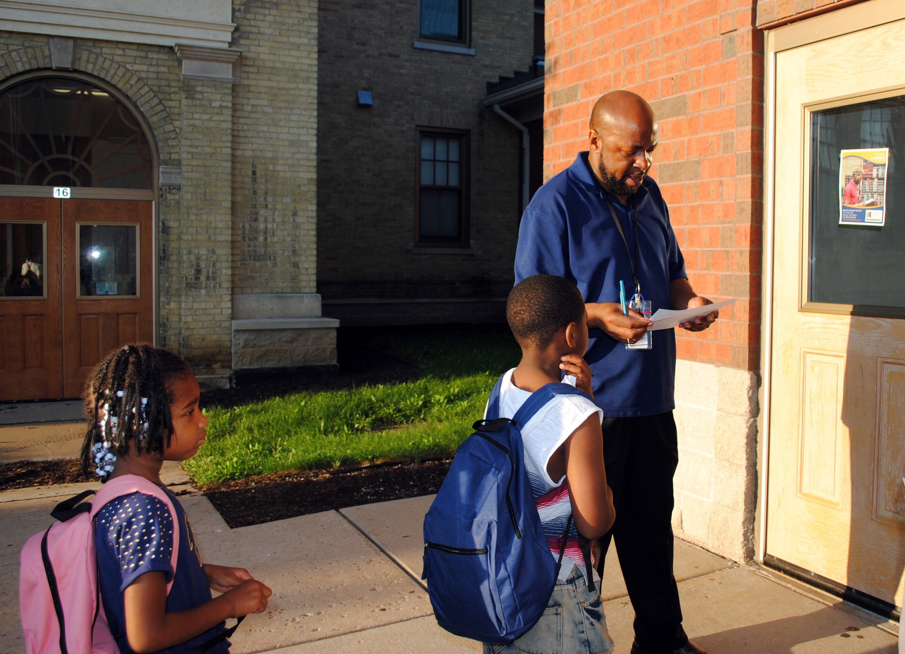 Edward Lawson checks to see if a student is on the list to enter the before-school activities program at Julian Thomas Elementary School in Racine, Wisconsin.