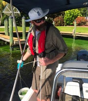 Researcher James Metcalf pulls up a sample of water from a North Fort Myers canal. He was on the Caloosahatchee researching toxic blue-green algae (cyanobacteria) that's been blooming in the river since June.