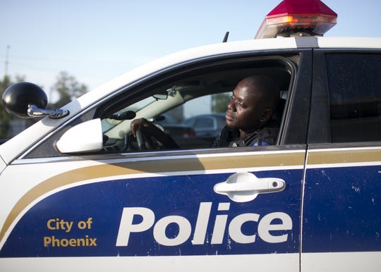 Germain Dosseh, a Phoenix police officer and Togolese refugee, sits in a patrol vehicle at the Phoenix Police Department headquarters on Wed. Aug. 15, 2018.
