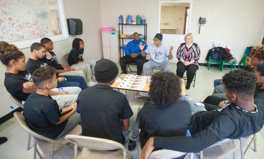 Christopher 2X (center) speaks while Kentucky education chief Wayne Lewis (left, in blue), YMCA official Jenny Benner (right) and Louisville teens listen at a Balling for a Cause meeting.