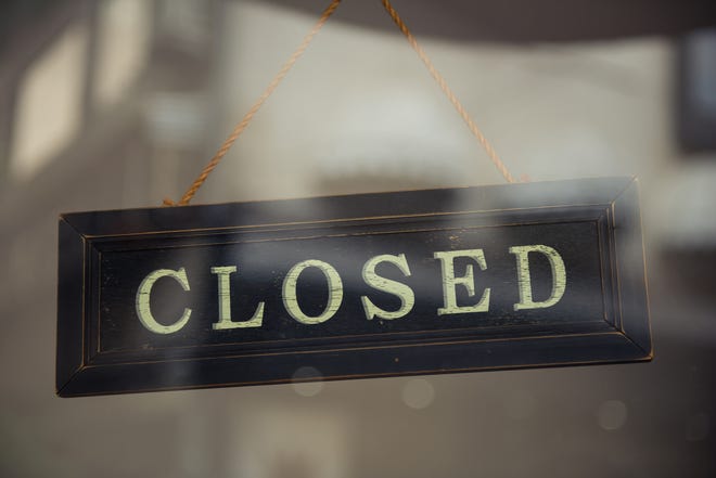 A close up of a 'CLOSED' sign hanging in a window