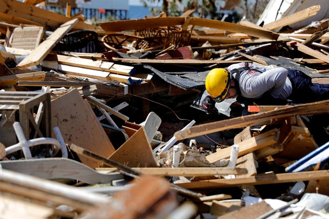 A member of a South Florida urban search and rescue team sifts through a debris pile for survivors of hurricane Michael in Mexico Beach, Fla., Sunday, Oct. 14, 2018.