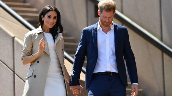 Britain's Prince Harry and his wife Meghan walk...
