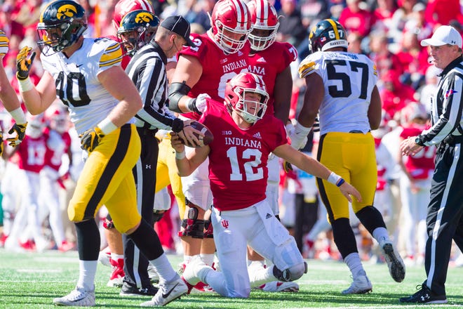 Indiana quarterback Peyton Ramsey (12) is helped to his feet by  teammates after being sacked by the Iowa defense in the first half of their game Saturday in Bloomington.