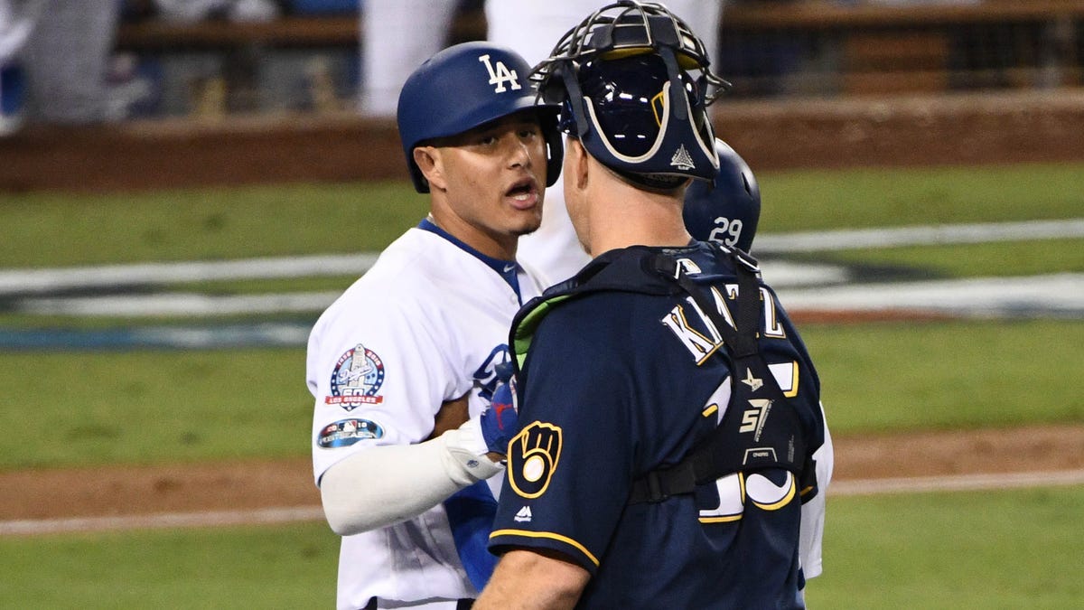 Dodgers shortstop Manny Machado and Brewers catcher Erik Kratz react after Machado clipped first baseman Jesus Aguilar on the way to first base.