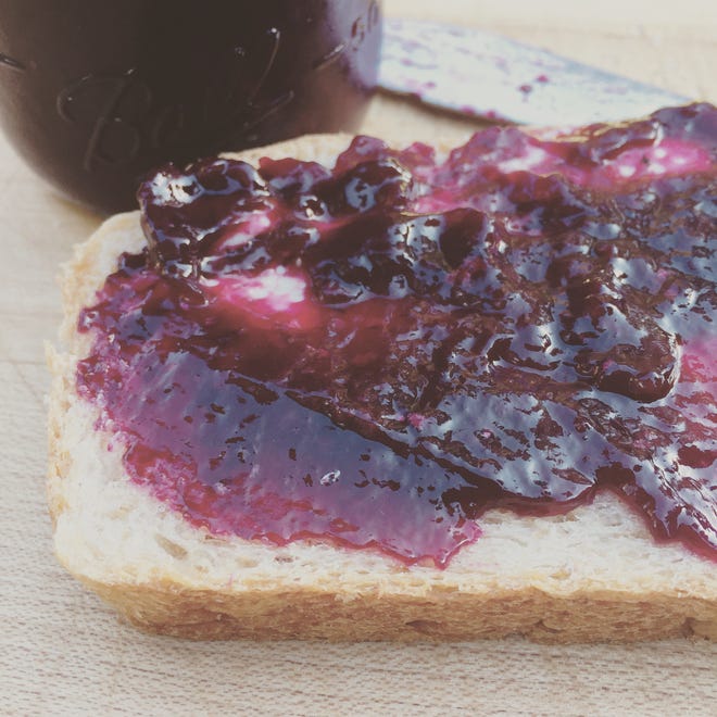 Everyday wheat bread is topped with some homemade grape jelly.