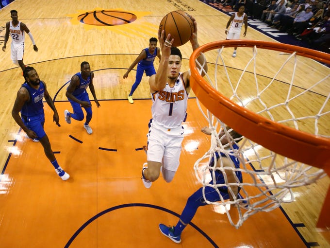 Phoenix Suns guard Devin Booker drives to the basket and scores against Dallas Mavericks Wesley Matthews during the season opener at Talking Stick Resort Arena on Oct. 17, 2018, in Phoenix, Ariz.