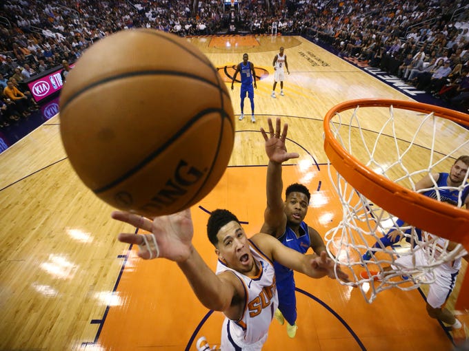 Phoenix Suns guard Devin Booker drives to the basket and scores against Dallas Mavericks Wesley Matthews during the season opener at Talking Stick Resort Arena on Oct. 17, 2018, in Phoenix, Ariz.