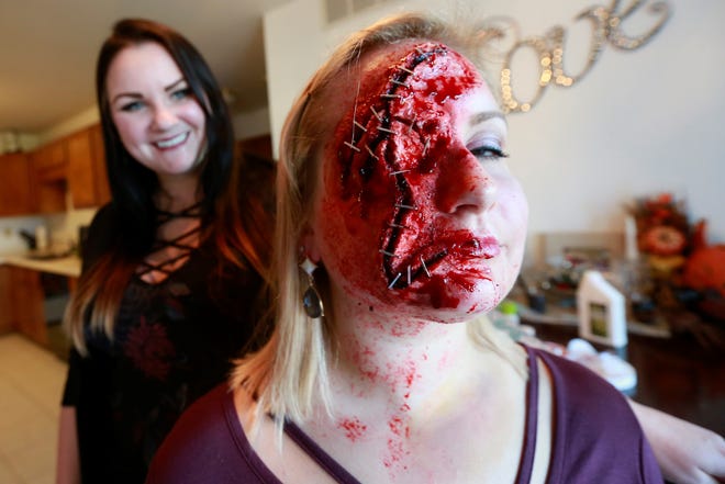 Special effects make-up artist Lacey Radomski, 29, left, looks on her 33-year-old sister Melissa Radomski poses for a photo Wednesday, Oct. 18, 2018, at her house in Plover, Wis.
