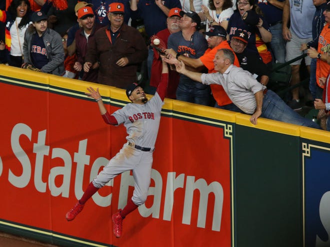 Red Sox right fielder Mookie Betts battles fans in the right field seats for a ball hit by the Astros' Jose Altuve. Umpires ruled the fans interfered with Betts and Altuve was called out.