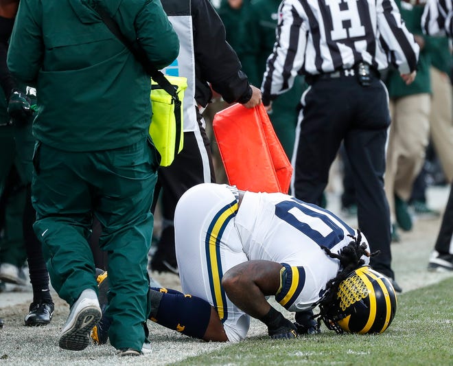 Michigan linebacker Devin Bush stays on the ground after tackling Michigan State running back LJ Scott during the first half at Spartan Stadium on Saturday, Oct. 20, 2018.