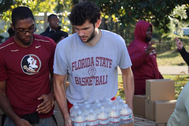 Sophomore forward Wyatt Wilkes and junior guard Trent Forrest help load water onto a truck.