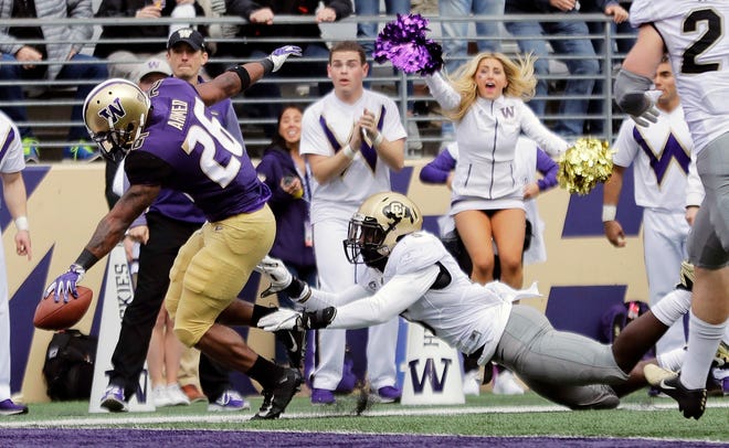 Washington running back Salvon Ahmed, left, scores a touchdown during Saturday's win over Colorado in Seattle.