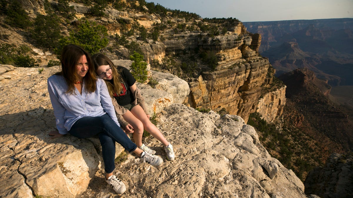 Laura Trujillo of Cincinnati, Ohio, sits on the ledge of the Trailview Overlook in Grand Canyon National Park with her daughter Lucy Faherty. Trujillo's mother, Elizabeth Miller, committed suicide by jumping off the Trailview Overlook in April 2012.
