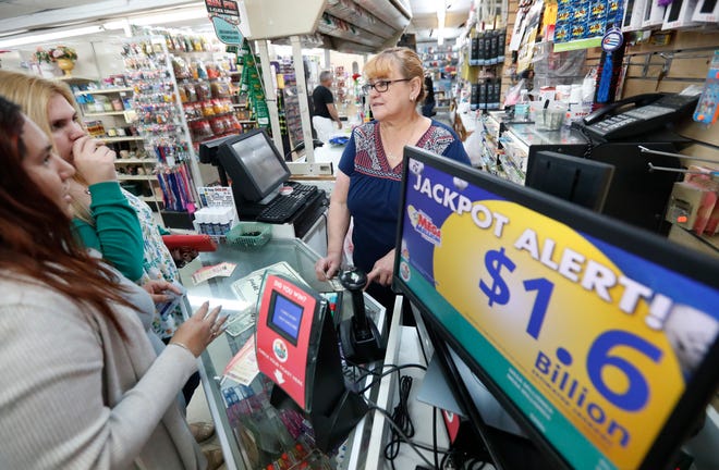 Daysi Lorenzo, center, sells lottery tickets, Monday, Oct. 22, 2018, at La Preferida Superdiscount store in Hialeah, Fla. Lottery players will have a chance at winning an estimated $1.6 billion jackpot in Tuesday night's Mega Millions drawing and an estimated $620 million in Wednesday night's Powerball jackpot.