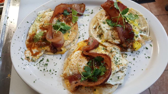 Fidler's on the Grand's Texas breakfast tacos include three over-easy eggs, bacon, cheddar cheese, cilantro, and the house hot sauce.