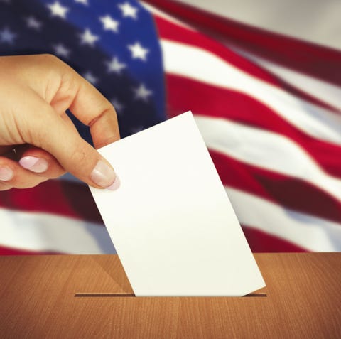 Hand putting a ballot into ballot box with america