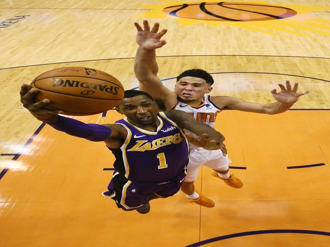 Los Angeles Lakers' Kentavious Caldwell-Pope dunks the ball against Phoenix Suns Devin Booker during a game on Oct. 24 at Talking Stick Resort Arena.