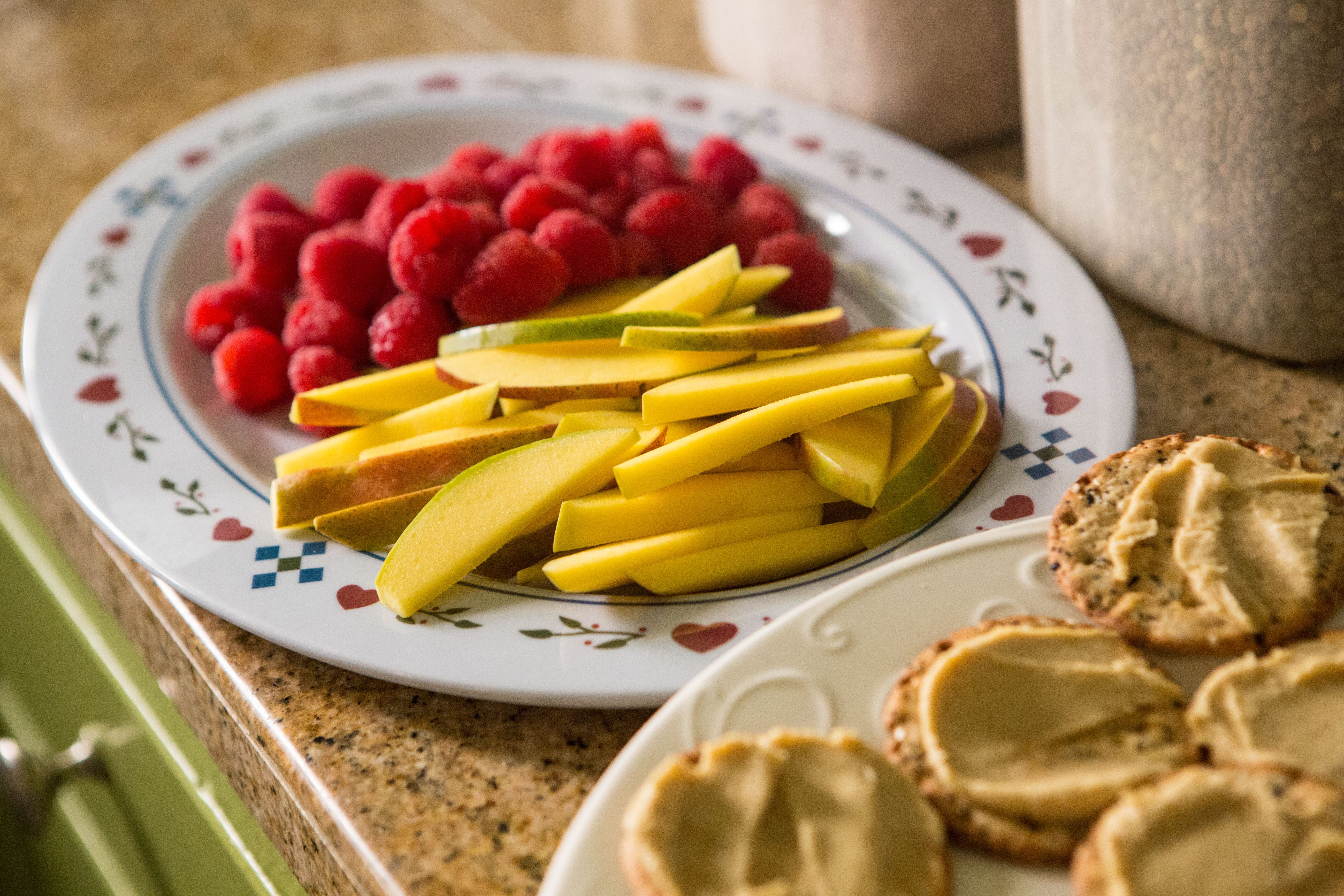 Hummus on multi-grain crackers and fresh mango and raspberries are prepared for snack at Shining Stars Family Child Care.