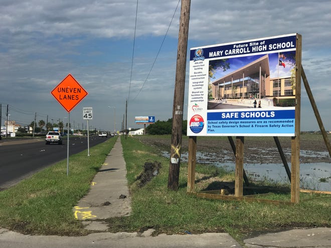 Two signs announcing the site of the new Carroll High School are set near a field on Saratoga Boulevard. One sign is next to a convenience store near Saratoga Boulevard and Weber Road, and another is near Most Precious Blood Catholic Church on Saratoga Boulevard.