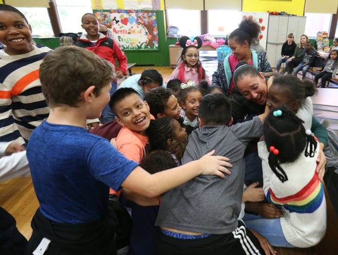 Students who participate in the after school program at Krieger Elementary School surround and hug after school program site supervisor Daisy Lee on October 25, 2018.