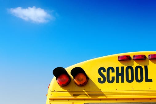Yellow school bus against vivid blue sky.