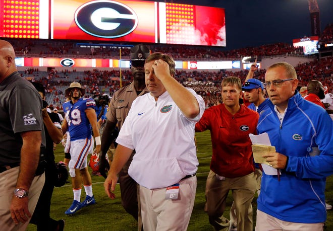 Florida Gators head coach Jim McElwain, center, walks off the field dejected after a defeat to University of Georgia in Jacksonville in 2017.