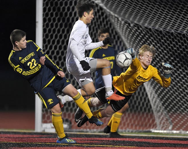 Spencerport goalie Jadon Schlierf, right, punches the ball clear of Brighton's Gabriel Barraclough-Tan, center and defender Frants Valodzka during a Class A sectional semifinal played at Hilton High School, Friday, Oct. 26, 2018.