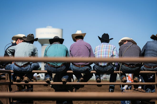 Cowboys sit on the railing to watch the calf roping during the 2018 Cinch Roping Fiesta.